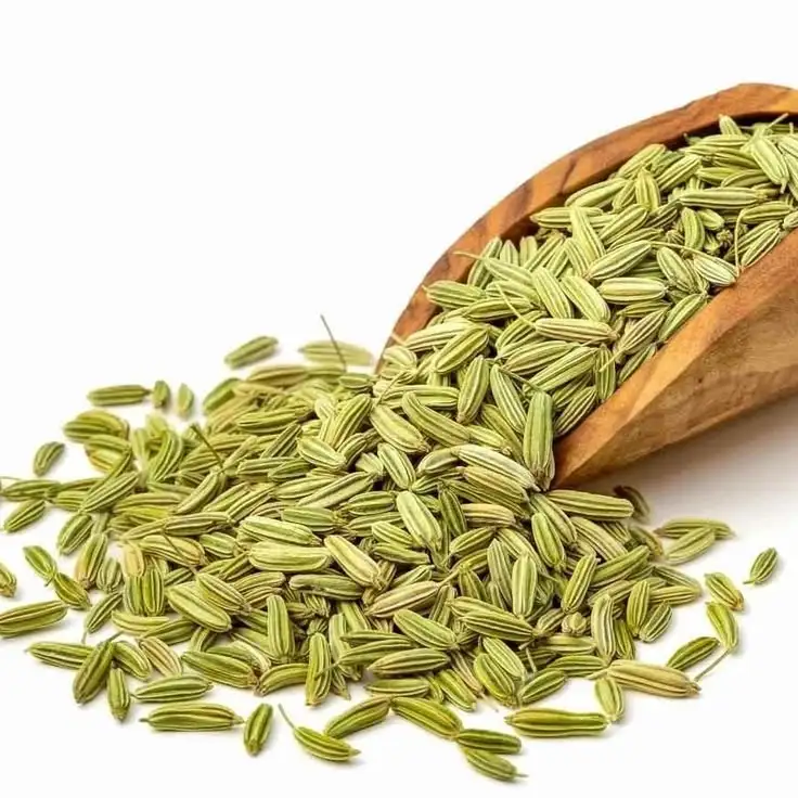 Green fennel seed spilling from a wooden scoop